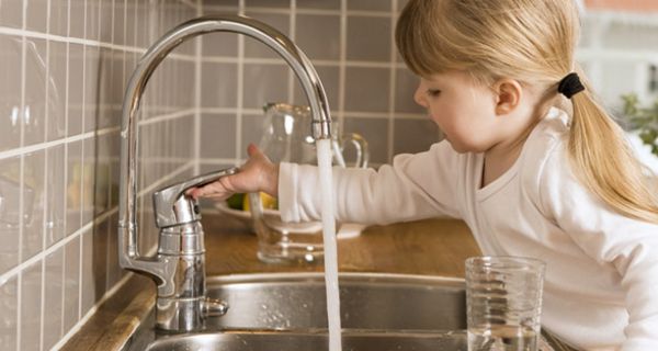 Mädchen dreht Wasserhahn auf.