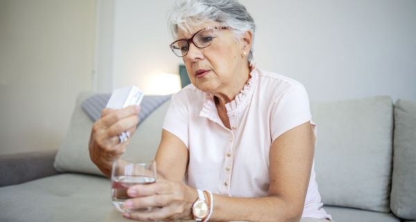 Frau betrachtet Medikamentenschachtel.