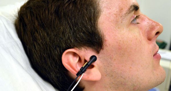 Clip einer TENS-Maschine am Ohr eines Probanden zur Stimulation des Vagusnervs