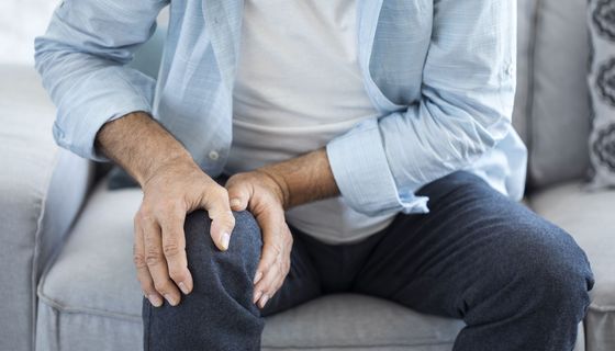 Mann, hält sich sein Knie.