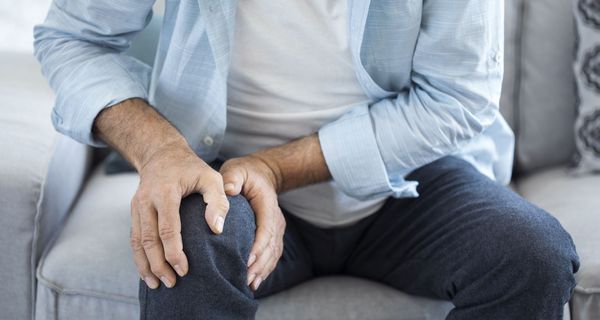 Mann, hält sich sein Knie.