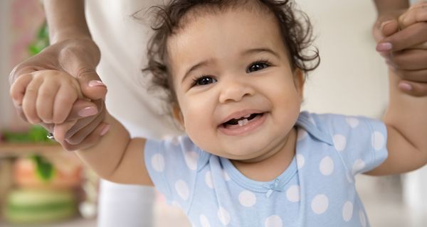 Baby, lächelt in die Kamera und zeigt die ersten Zähne.