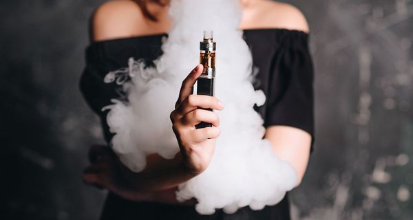 Frau mit einer E-Zigarette, umgeben von Dampf.