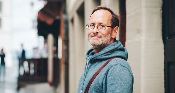 Älterer Mann in Freizeitkleidung auf einer Straße.