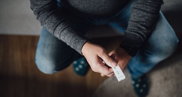 Mann, hält Antigen-Schnelltests in der Hand.