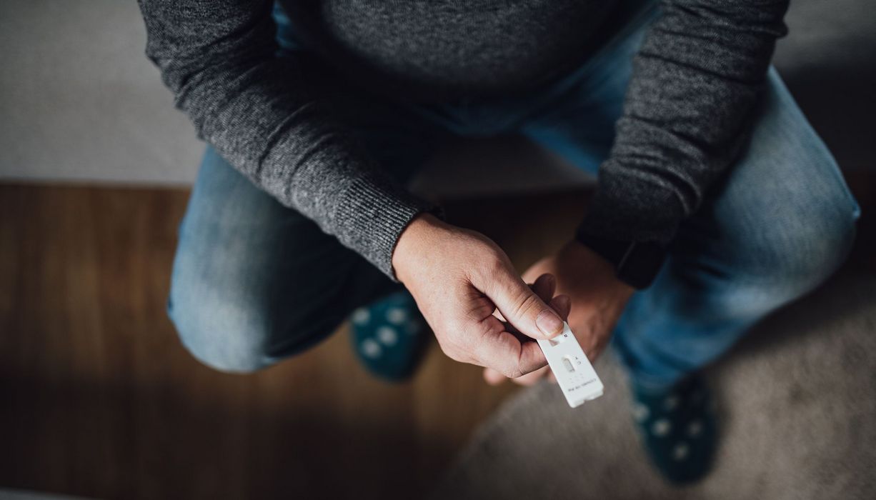 Mann, hält Antigen-Schnelltests in der Hand.