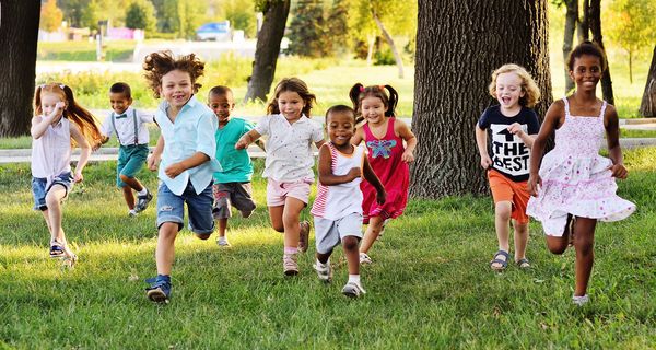Eine Gruppe Kinder rennt auf einer Wiese.