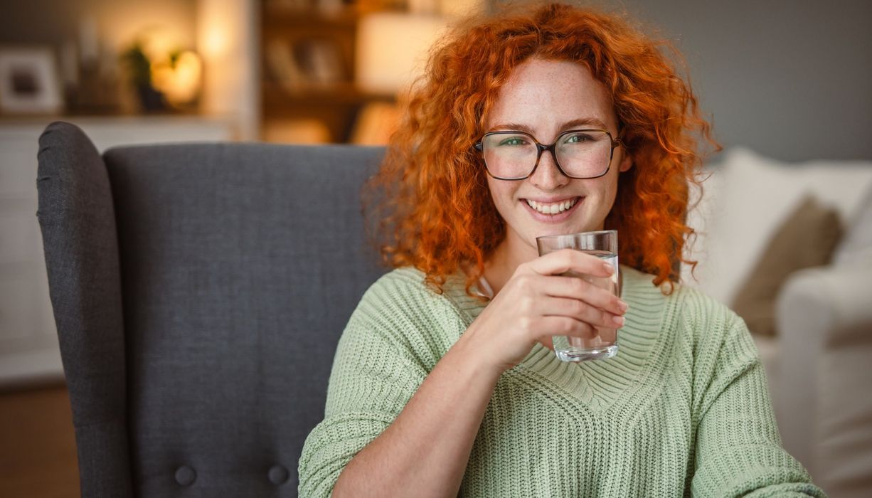 Junge Frau, trinkt ein Glas Wasser.
