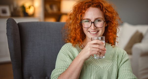 Junge Frau, trinkt ein Glas Wasser.