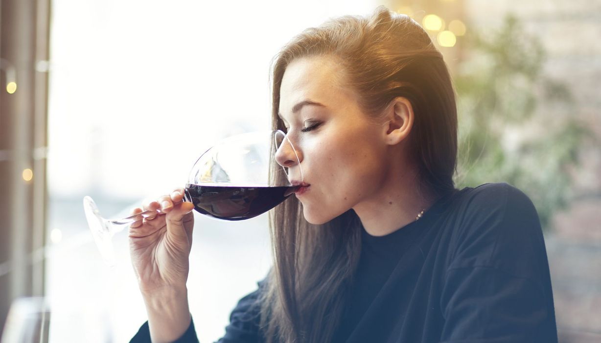 Junge Frau trinkt ein Glas Rotwein.