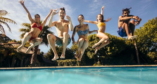 Jugendliche springen in einen Swimming Pool.