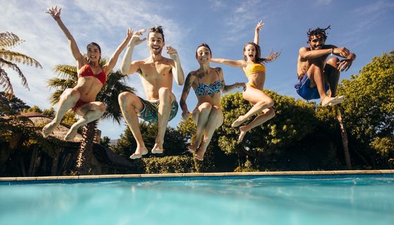Jugendliche springen in einen Swimming Pool.