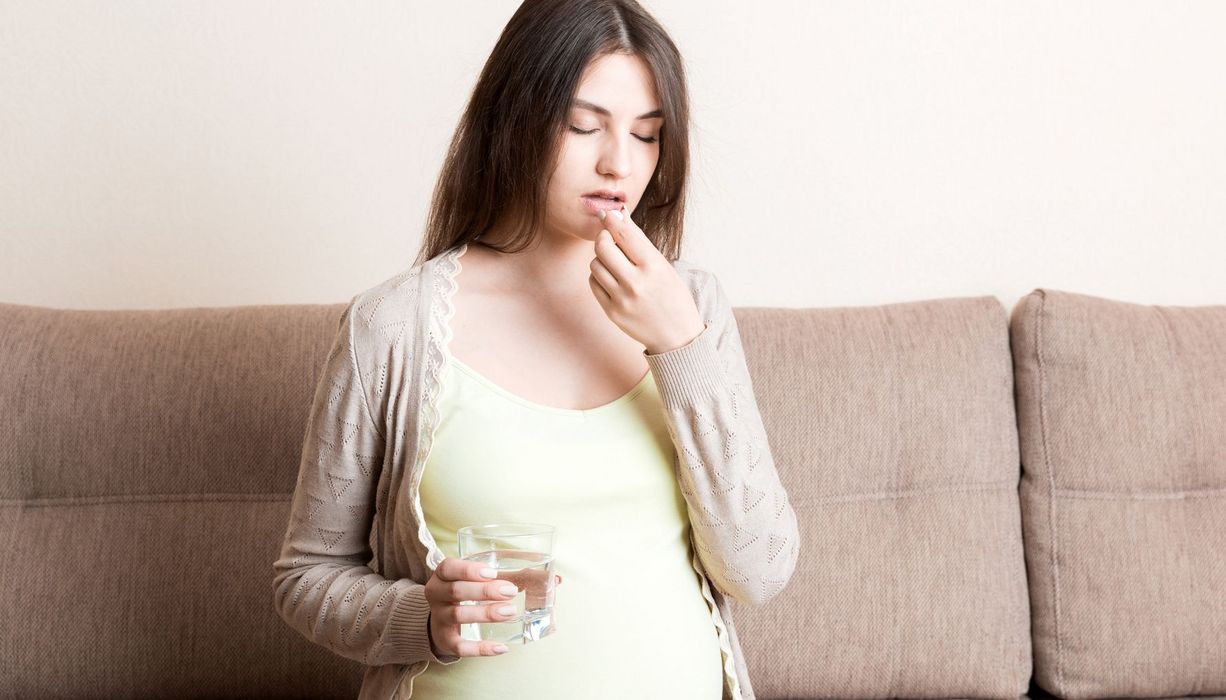 Eine Schwangere nimmt ein Medikament ein.