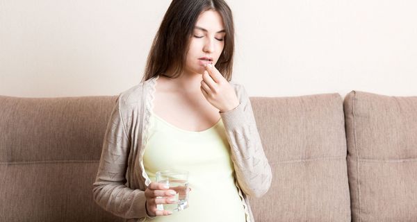 Eine Schwangere nimmt ein Medikament ein.