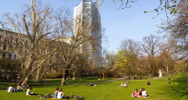 Stadtpark mit Menschen auf der Wiese im Hintergrund ein Hochhaus