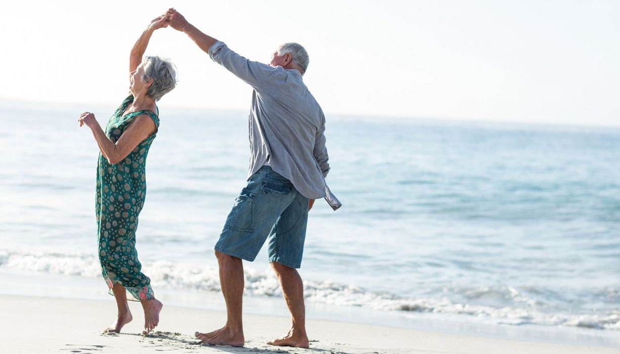 Zwei ältere Senioren, tanzen am Strand.