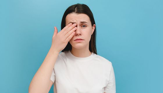 Frau, hält sich ein Auge.