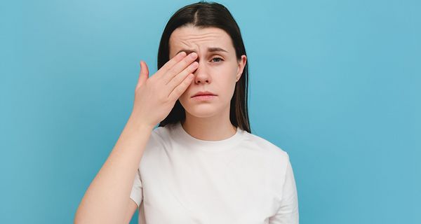 Frau, hält sich ein Auge.
