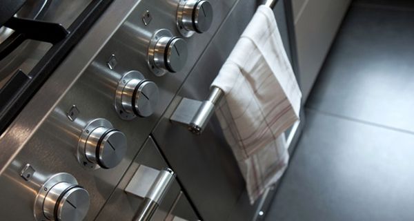 Profiküchengasherd aus Edelstahl, schräg fotografiert, mit Küchenhandtuch über Ofengriff hängend
