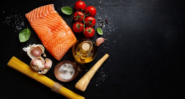 Lachs, Tomaten und Pasta auf einem dunklen Hintergrund.