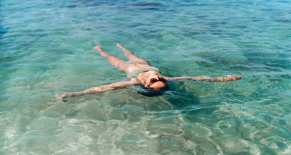 Frau, liegt im Meer rauf dem Rücken und lässt sich treiben.