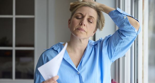 Frau, fächert sich Luft mit einem Blatt Papier zu.