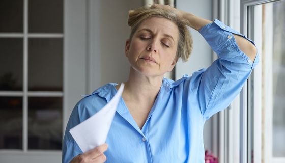 Frau, fächert sich Luft mit einem Blatt Papier zu.