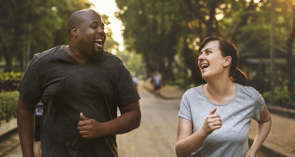 Ein Paar joggt gut gelaunt, beide sehen nicht sehr fit aus.