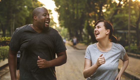 Ein Paar joggt gut gelaunt, beide sehen nicht sehr fit aus.