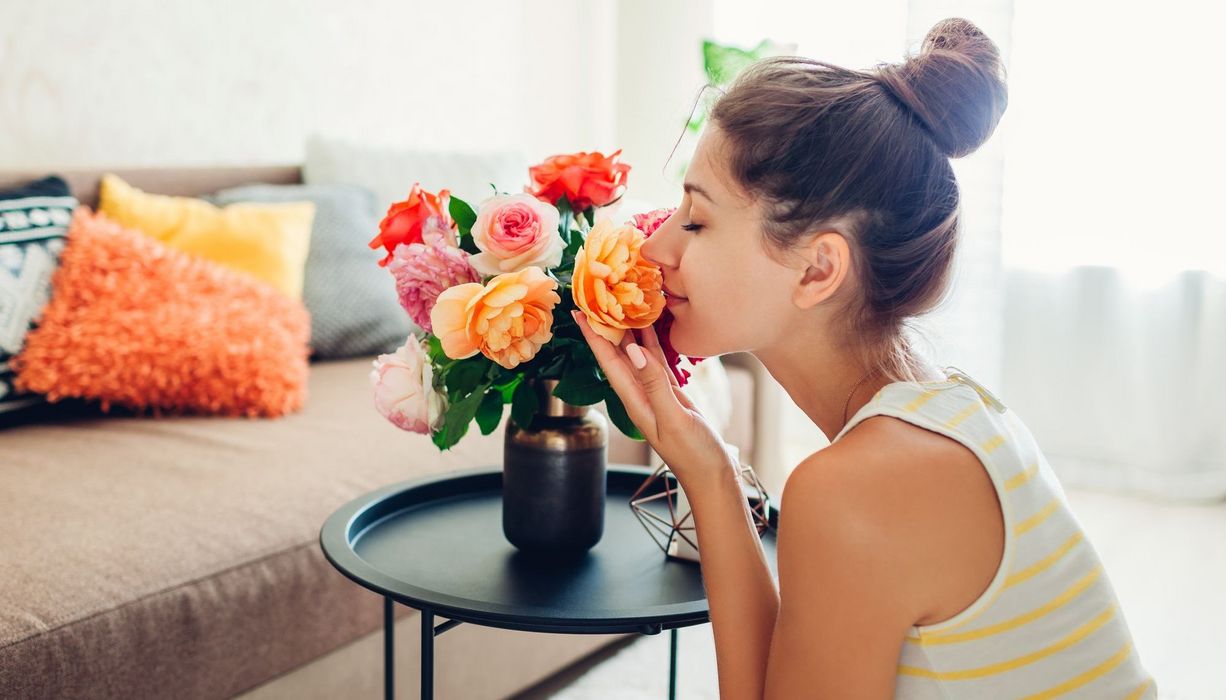 Junge Frau, riecht an Blumen.
