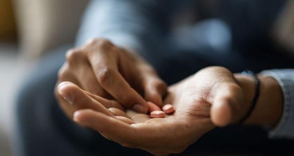 Mann, hält Tabletten in seiner Hand.
