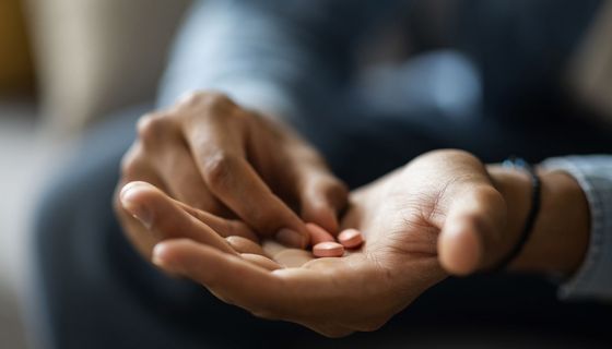 Mann, hält Tabletten in seiner Hand.
