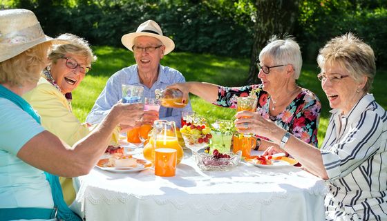 Gruppe von Senioren frühstückt im Freien.