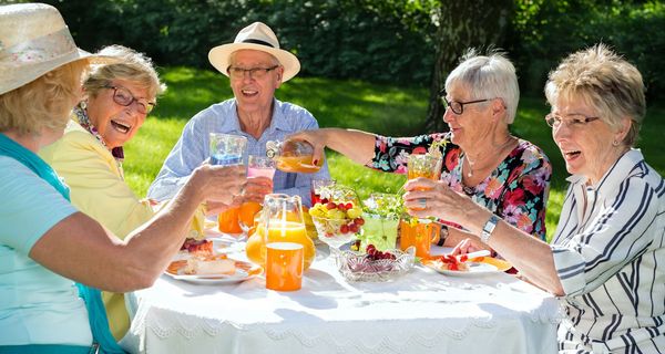 Gruppe von Senioren frühstückt im Freien.
