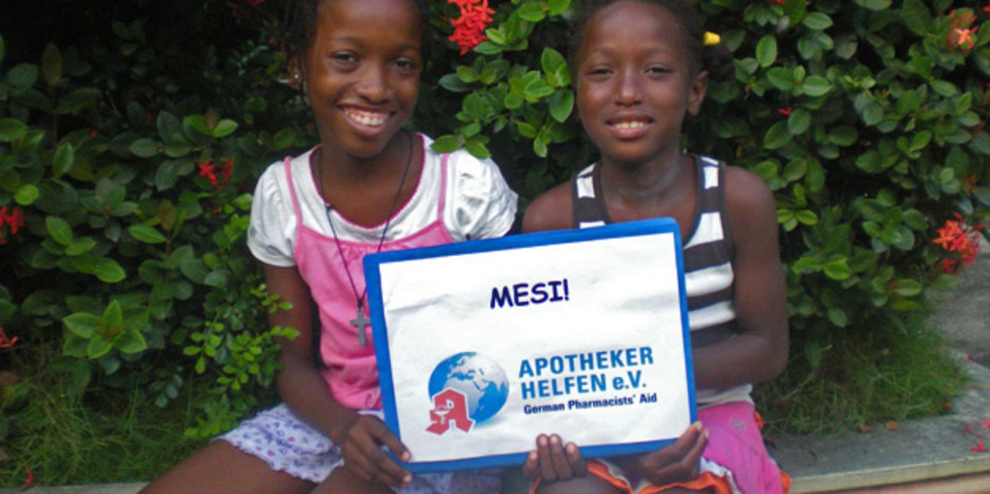 Zwei haitianische Mädchen halten ein Dankes-Plakat in die Kamera