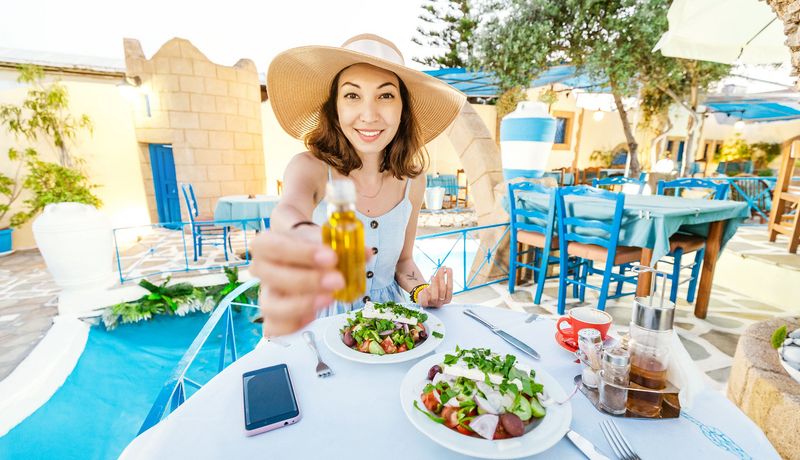 Frau mit Strohut isst einen Salat in mediterranem Restaurant.