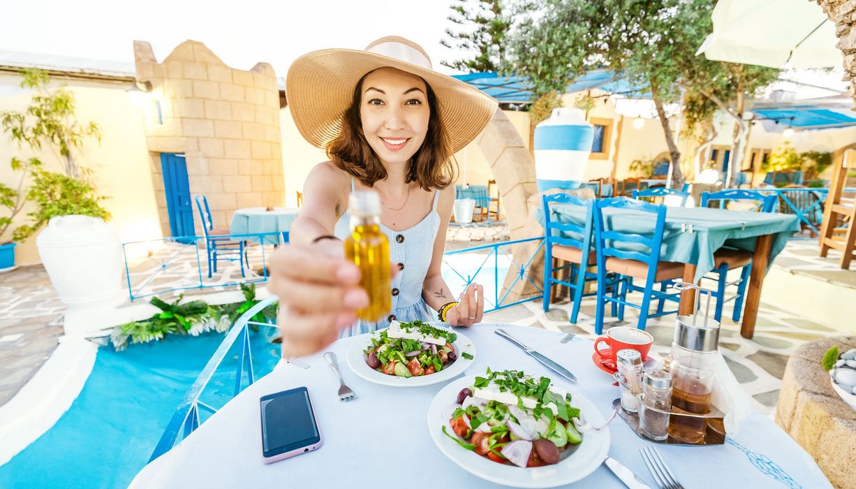 Frau mit Strohut isst einen Salat in mediterranem Restaurant.