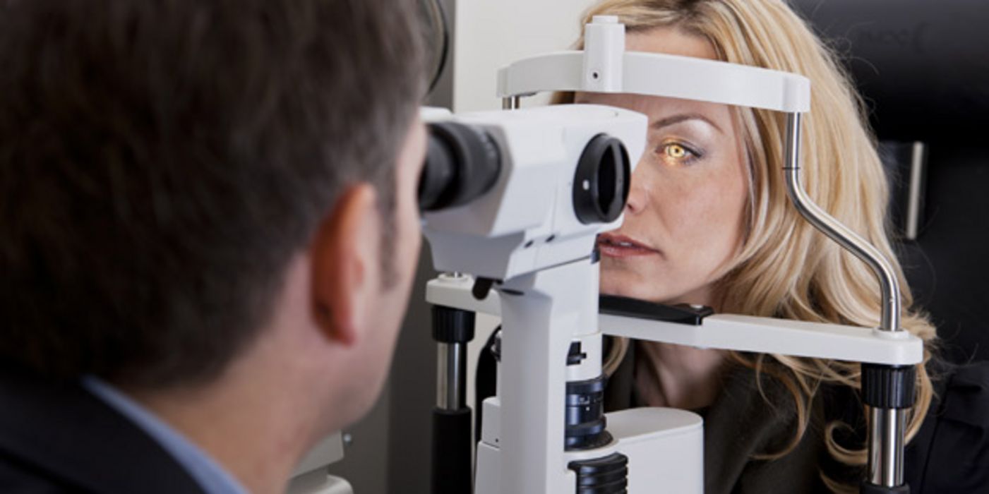 Arzt untersucht das Auge einer Patientin mit einer Spaltlampe