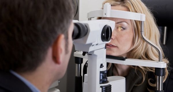 Arzt untersucht das Auge einer Patientin mit einer Spaltlampe
