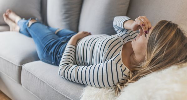 Frau liegt auf dem Sofa.