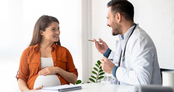 Eine schwangere Frau lässt sich von einem Arzt beraten.