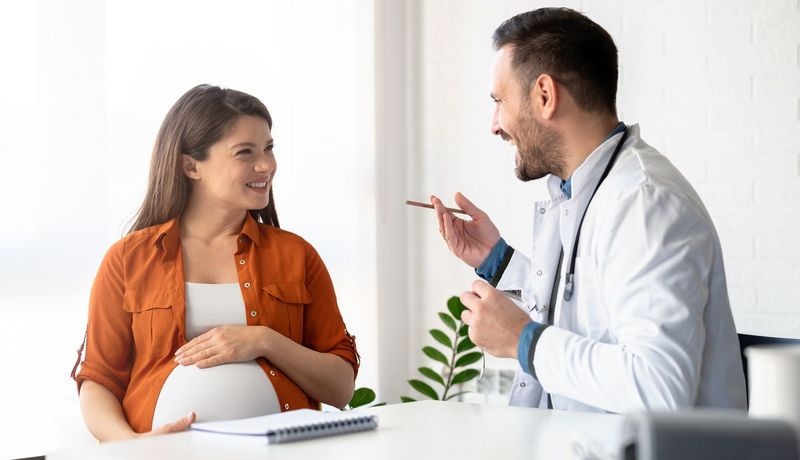 Eine schwangere Frau lässt sich von einem Arzt beraten.