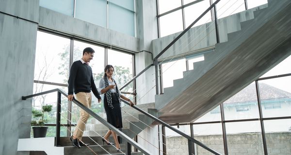 Ein Mann und eine Frau gehen in einem Bürogebäude die Treppe herunter.