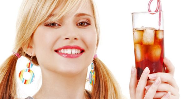 Blonde junge Frau hält ein Cola-Mixgetränk mit Eiswürfeln in den Händen