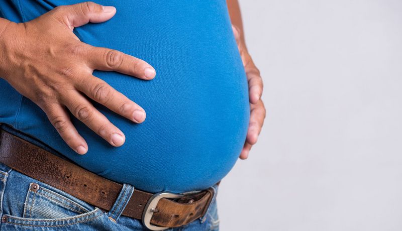 Mann legt seine Hände auf den Bauch in Seitenansicht.