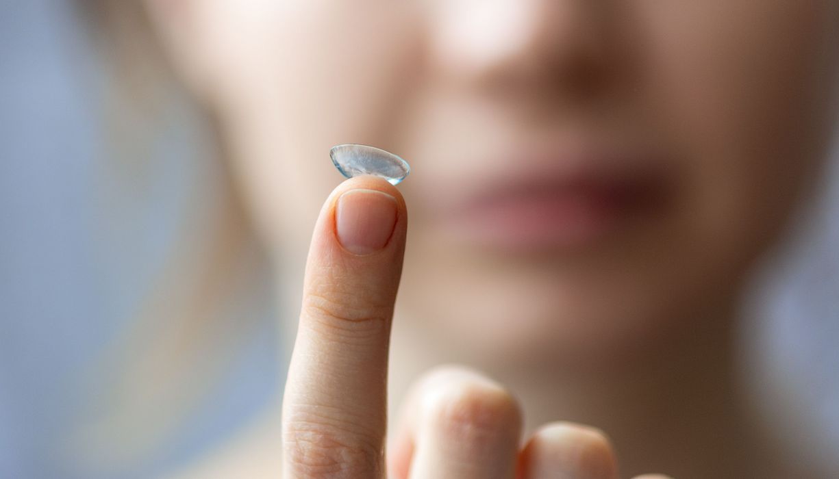 Mädchen hält eine Kontaktlinse auf dem Finger.