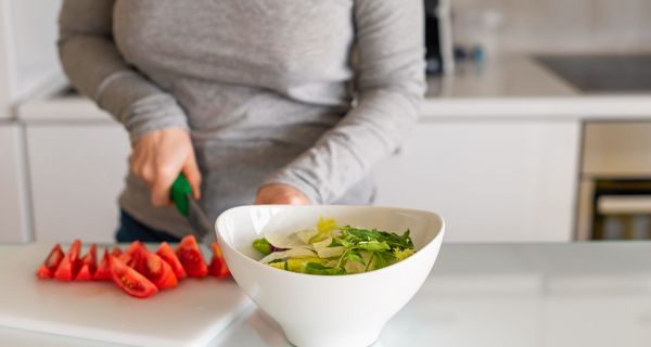 Frau, schneidet Tomaten und macht sich einen Salat.