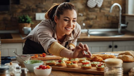 Junge Frau, bereitet Baguettes mit Aufstrich vor.