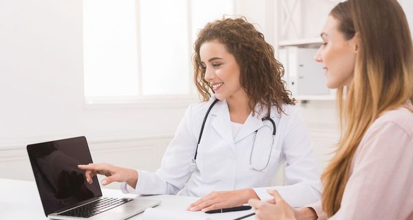 Ärztin zeigt Patientin etwas auf dem Laptop.