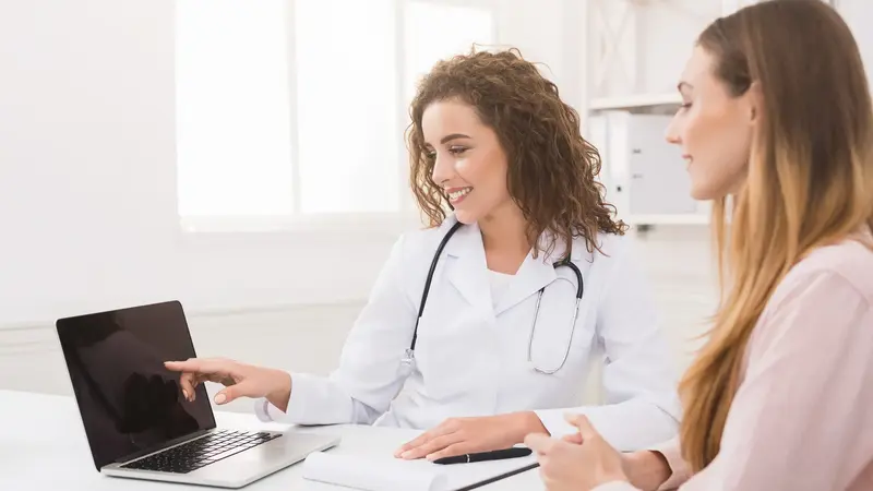 Ärztin zeigt Patientin etwas auf dem Laptop.
